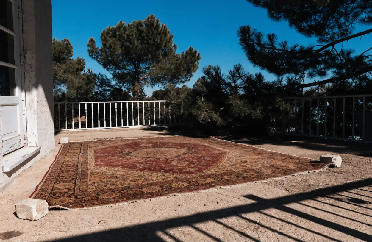 Grand tapis persan séchant à plat sur une terrasse au soleil